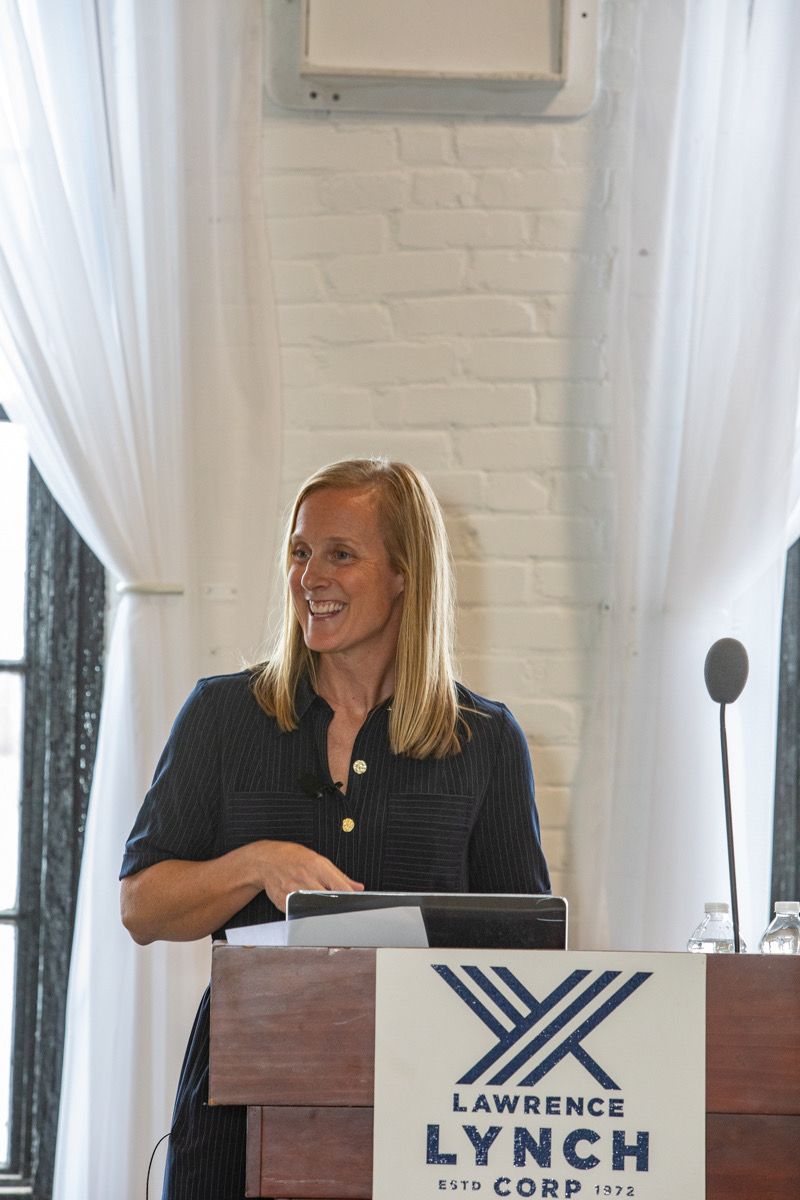 Ashley Katzenback speaking at a podium at a Lawrence Lynch Corp event